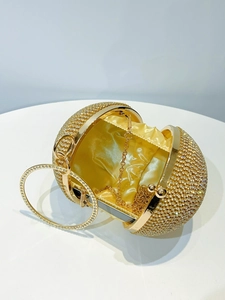 Macro view of gold evening bag with rhinestones, satin lining and round ring handle