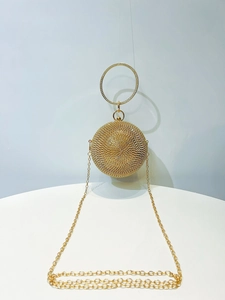 Macro view of a gold spherical evening bag featuring shimmering rhinestones and a metal handle