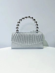 Detail of silver glitter evening clutch featuring metallic beaded circular top handle