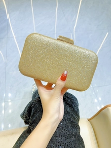 Macro detail of the golden sequin finish and rectangular metal clasp on the evening clutch