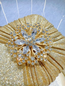 Macro shot of gold sequin clutch with large crystal flower ornament detail
