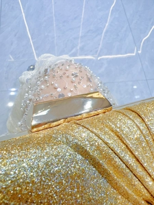 Close-up of a sparkling gold evening clutch bag paired with a beaded lace party dress