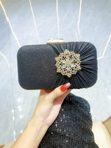 Detail of black satin evening clutch with sparkling rhinestones and crystal flower buckle