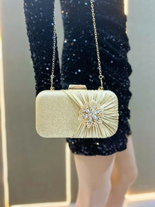Detail of luxury gold evening clutch with rhinestones and elegant pleated glitter texture