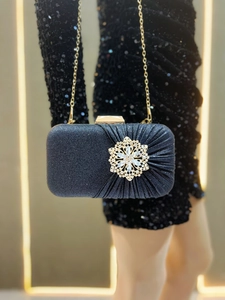 Detail of black glitter evening clutch with vintage gold floral buckle and metal chain