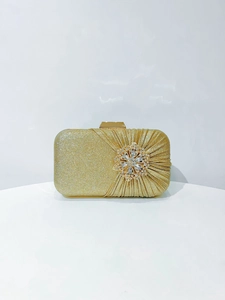 Detail of golden glitter evening clutch with rhinestone flower and pleated design