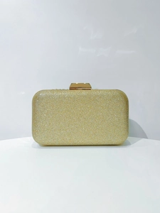 Close-up of sparkling gold glitter surface and metallic clasp on evening clutch bag