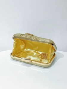 Detail of gold glitter evening clutch with crystal clasp, satin lining and chain strap