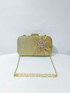 Detail of gold glitter clutch with crystal flower clasp and gold chain strap