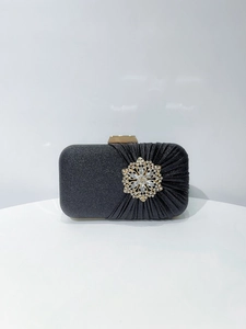 Close-up of asymmetric black evening bag with pleated silk and sparkling rhinestone flower