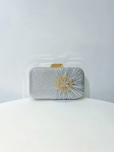 Macro detail of silver glitter fabric and elegant gold flower rhinestone buckle on clutch