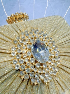 Detail of gold glitter evening clutch with large clear rhinestones and vintage crown clasp