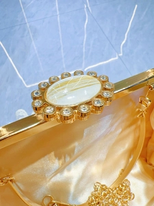Macro detail of gold evening clutch featuring rhinestone lock and marble stone inlay