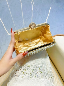 Elegant gold evening clutch bag with white pearl trim and diamond-encrusted ring clasp
