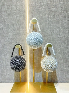 Elegant spherical pearl evening bags with metal ring handles in blue, black, and white