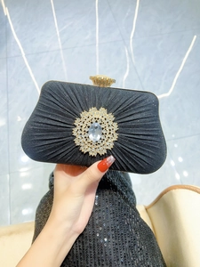 Detail of a black pleated evening clutch featuring a large crystal floral centerpiece