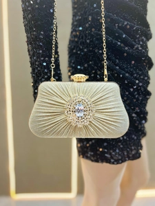 Detail of gold pleated evening clutch with crystal flower clasp and elegant chain