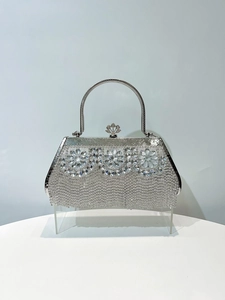 Macro detail of silver evening bag featuring crystal flower patterns and crown clasp