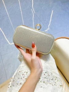 Detail of champagne gold evening clutch with rhinestone ring clasp and silk texture