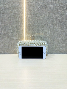 Detail showing pearl evening clutch bag compared with smartphone for size reference