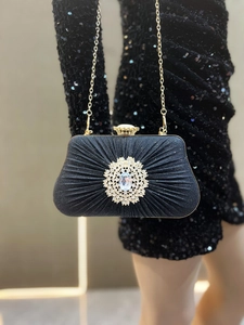 Detailed view of black pleated evening clutch with large radiant rhinestone flower ornament
