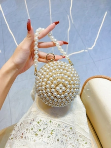 Close-up of spherical pearl evening bag with floral rhinestone accents and gold hardware