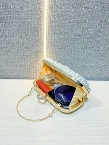 Detail of evening clutch interior with satin lining, perfume and luxury pearl trim