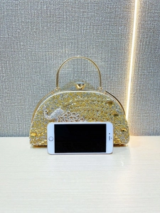 Detail of evening clutch bag featuring gold rhinestones and crystal peacock clasp