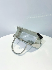 Detail view of silver metal evening bag with vintage texture and white satin lining