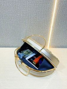 Inside view of a gold rhinestone evening clutch showing phone, perfume and lipstick storage