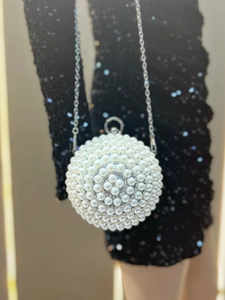 Detail of spherical evening bag with dense pearl embellishments and silver chain strap