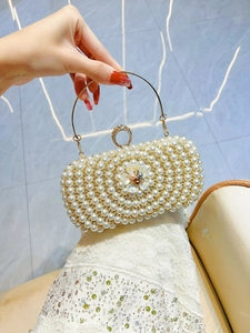 Detailed close-up of pearl evening clutch with gold ring handle and floral embellishment