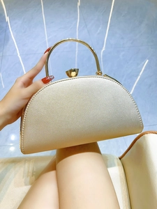 Detail of champagne gold evening clutch with top ring handle and flower clasp