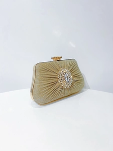 Close-up of champagne gold pleated evening bag with sunflower rhinestone buckle detail