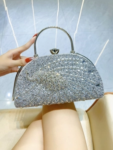 Detailed view of a silver peacock clutch bag with sparkling rhinestones and metal ring handle
