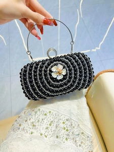 Detail of black evening clutch with pearl beads, floral decor and rhinestone ring handle