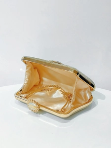Detail view of champagne gold evening clutch bag with silk lining and detachable chain