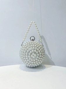 Macro view of spherical pearl evening bag showing luxury beaded detail and silver metal clasp