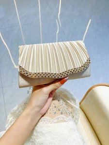 Détail de la pochette de soirée en satin doré champagne avec strass et plis élégants