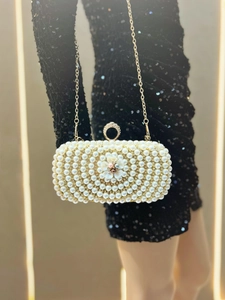 Detail of evening clutch featuring white pearls, rhinestones, and 3D flower clasp