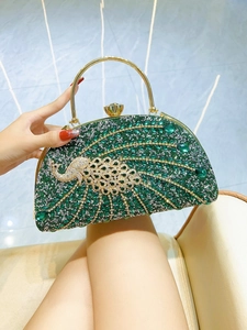 Detail of emerald peacock evening clutch with intricate rhinestones and gold ring handle
