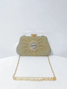 Macro detail of gold pleated fabric texture and luxury crystal buckle on evening bag