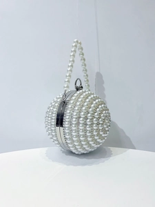 Detailed macro of a spherical clutch bag featuring white pearls and sparkling rhinestones