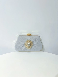 Detailed view of pleated evening clutch with crystal sunflower brooch and gold metal frame