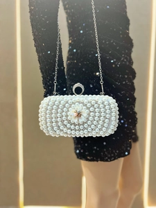 Detailed close-up of a white pearl clutch with a floral accent and silver chain strap