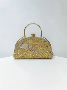 Detail of golden evening clutch with crystal peacock pattern and jewel clasp