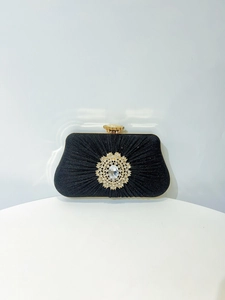 Detail of black pleated evening clutch with crystal flower decor and gold frame