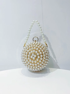 Detail of spherical evening bag featuring white pearls and a gold metallic ring handle