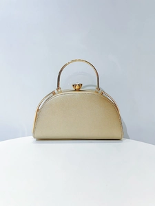 Close-up of golden semi-circular evening bag with shimmering texture and crystal clasp