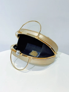 Detail of oval evening clutch with rhinestone flower clasp and gold metal handles